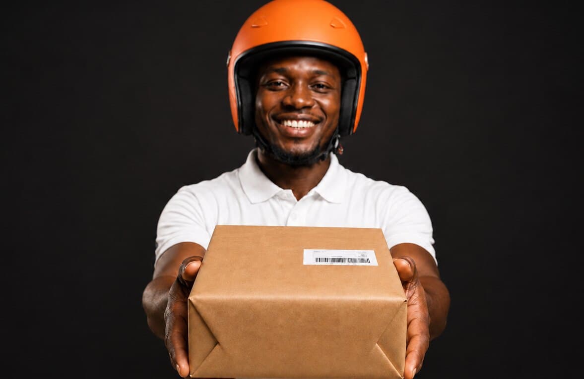 A delivery rider presenting a labelled parcel — your order, shipped and out for delivery